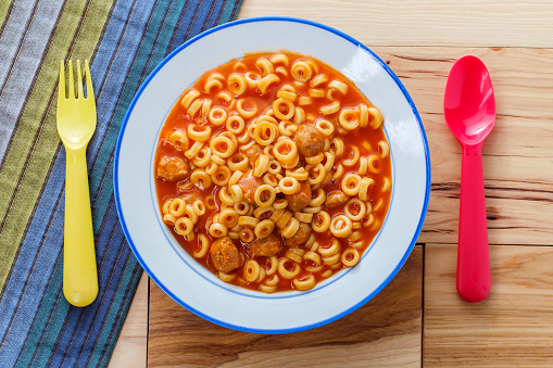 Canned children's meal spaghetti rings with meatballs and colorful utensils