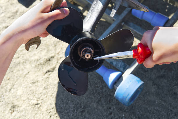 man changing propeller on outboard motor. Repairing outboard motor for boat, replacing screw. man changing propeller on outboard motor. Repairing outboard motor for boat, replacing screw motorboat maintenance stock pictures, royalty-free photos & images