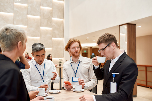 Group of businesspeople interacting during coffee break at business conference. Business, communication concept. Horizontal shot. Selective focus