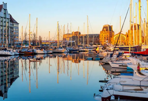 The yacht harbor of Oostende (Ostend) with train station at sunset, Belgium.