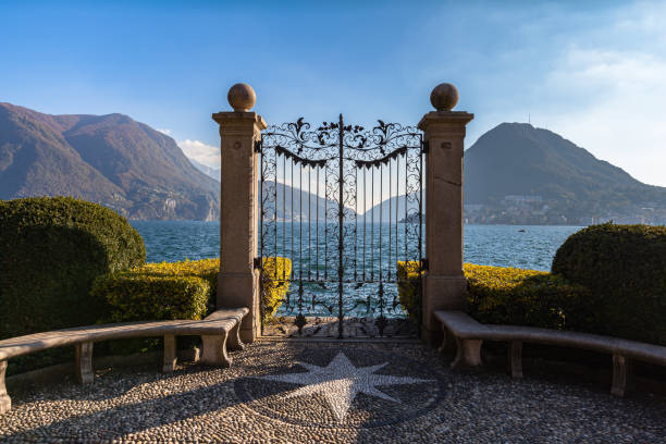 Panorama view of Lugano Lake from gate of Cancello sul Lago di Lugano in Parco Ciani park Stunning panorama view of Lugano Lake with Monte San Salvatore in background from gate of Cancello sul Lago di Lugano in Parco Ciani park on sunny autumn day, Canton of Ticino, Switzerland lugano stock pictures, royalty-free photos & images