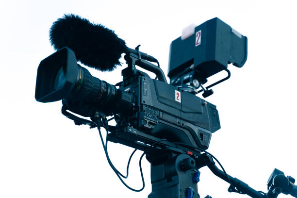 istock The video camera with the microphone is standing on the tripod isolated on white, in concept of technology, modern, entertainment. 1264562956