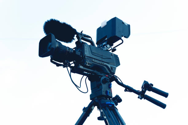 istock The video camera with the microphone is standing on the tripod isolated on white, in concept of technology, modern, entertainment. 1264563081
