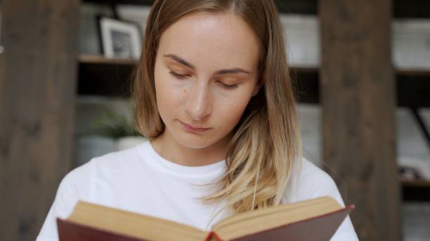 istock Beautiful young woman reading a book on the sofa 1264563674