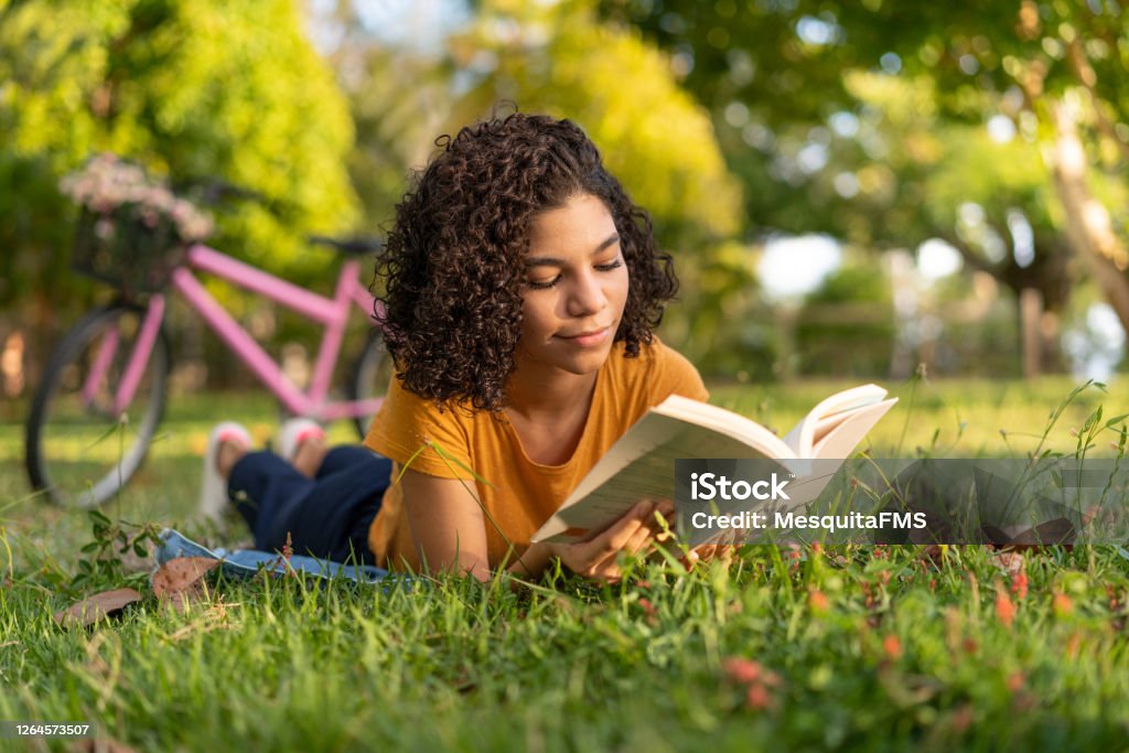 躺在草地上看書的特恩女孩。 - 免版稅讀圖庫照片