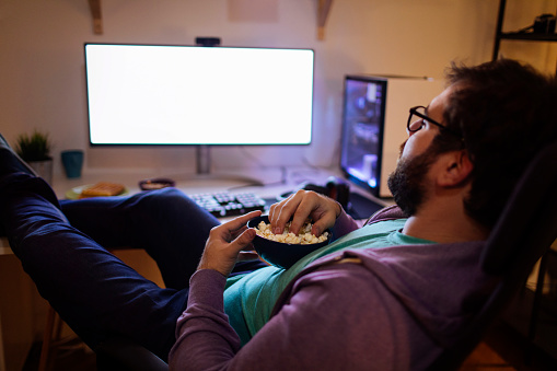 Bearded man having a snack in front of his desktop computer