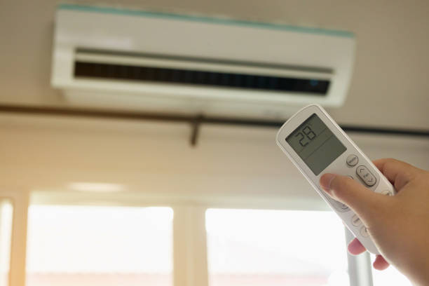 istock Hand with remote control directed on air conditioner inside the room 1264580484