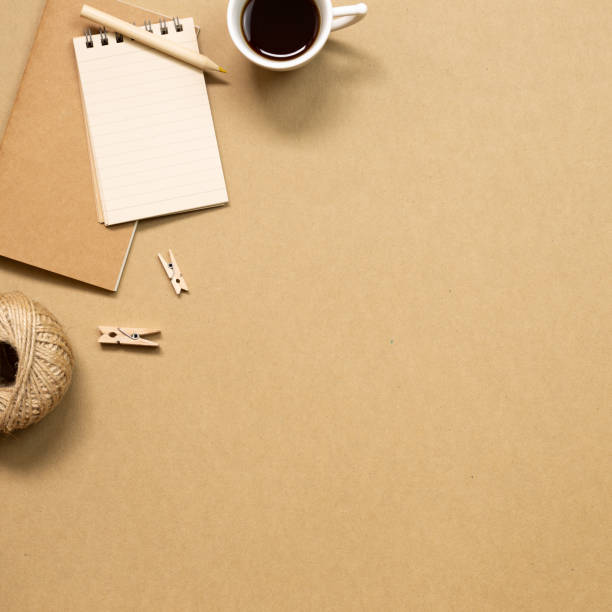 istock Notebook and black coffee on brown kraft paper background. flat lay, top view, copy space. Work and study place 1264581152