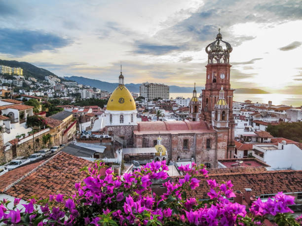 Guadalupe Church scene with fuchsia flowers. Famous Guadalupe Church with ocean and mountains in background framed with fuchsia buganvilla bushes in Puerto Vallarta Mexico. fuchsia flower photos stock pictures, royalty-free photos & images