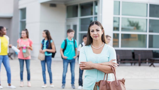 istock Hispanic teacher standing outside middle school 1264588551