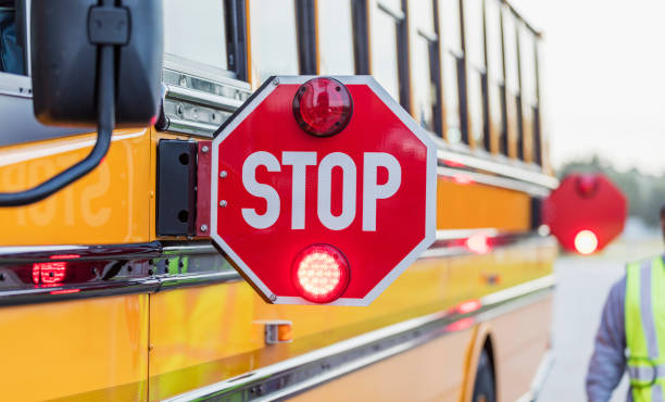 School bus stop sign A yellow school bus stopped on the side of the road with stop signs out and flashing. empty school bus stock pictures, royalty-free photos & images