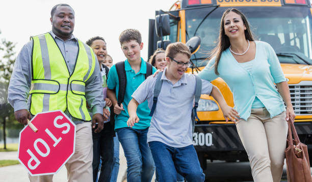 istock Students, teacher, boy with down syndrome by school bus 1264589932
