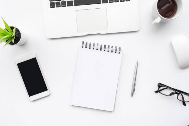 istock White office desk table with white smartphone with blank screen, notebook, laptop computer and supplies. Top view, flat lay. 1264593595