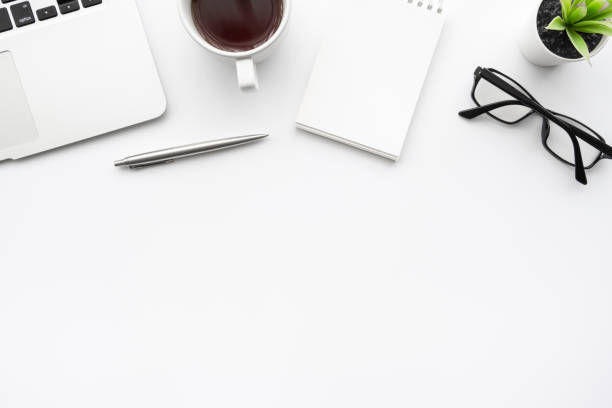 istock White office desk table with laptop computer, blank notebook page, cup of coffee and supplies. Top view with copy space, flat lay. 1264593598