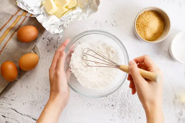 Baking and cooking pastry or cake ingredients, flour sugar eggs and butter, on white marble background. Top view.