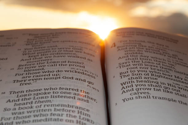 istock Holy Bible open at sunset with highlight on Malachi 4:2. Background with clouds and sun 1264596144