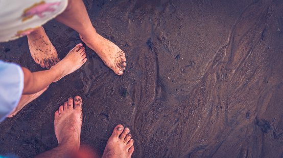 Bare foot on the beach. Couple with their kid having fun on the beach. POV; copy space
