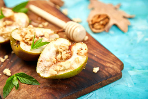 Tasty roast pears with honey and walnuts on blue background table.