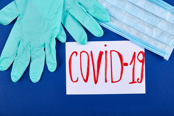 istock Coronavirus phrase text flat lay on blue background, gloves protective face mask 1264606371