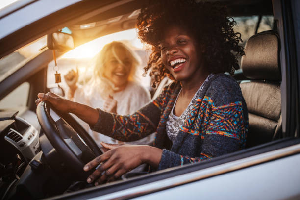 Road trip with best friend Two young cheerful female friends having fun on road trip in car at sunset car interior stock pictures, royalty-free photos & images