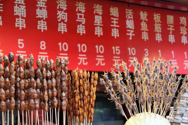 Wangfujing Snack Street in Beijing, China On a red menu board shows the prices of insects are from 1 to 15 Chinese yuan(0.15 to 2.15USD) per stick. wangfujing stock pictures, royalty-free photos & images