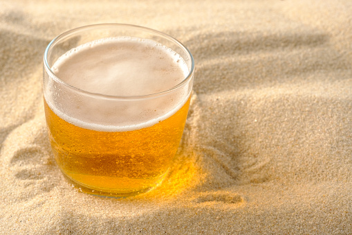 Beach vacation concept. Cool drinks on the beach sand. Cold foamy beer.