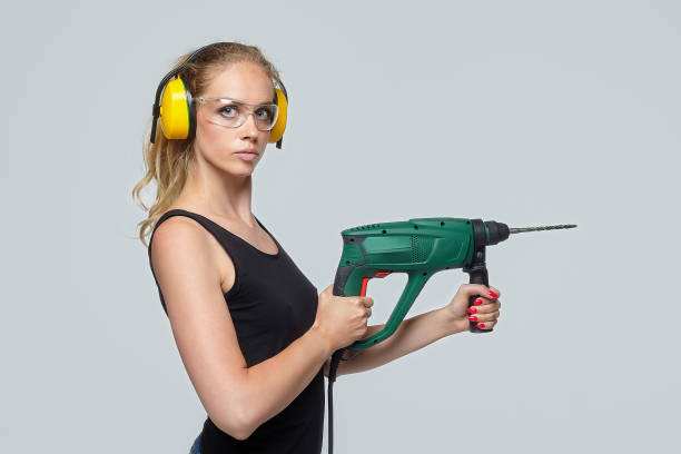 fille blonde. posant dans le studio sur un fond blanc, tenant une perceuse. concept de construction - engineer occupation women industrial photos et images de collection