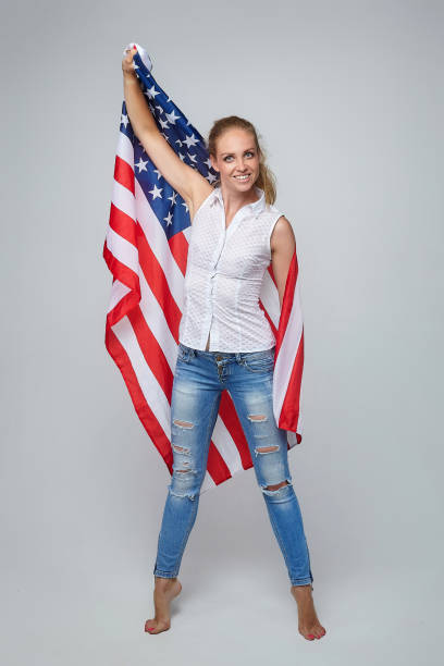 istock blonde girl. posing with usa flag in studio on white background 1264614909