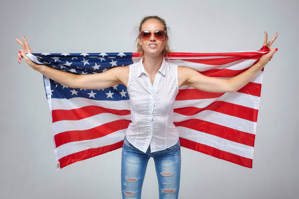 istock blonde girl. posing with usa flag in studio on white background 1264614914