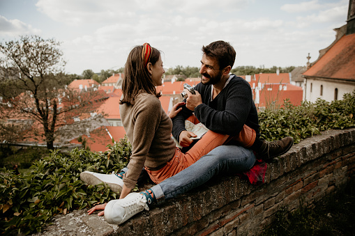 Loving smiling couple sitting on the wall and deciding what to explore next.