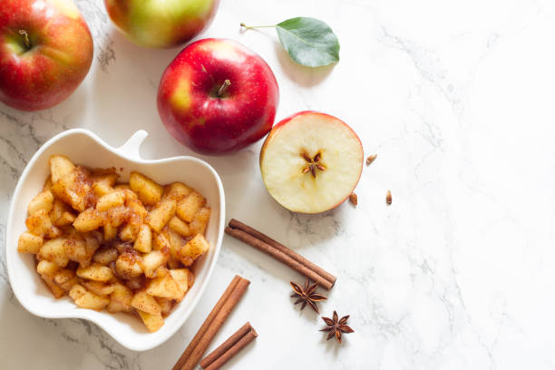 äpfel, zimt und klobige apfelsauce auf weißem hintergrund - stewed fruit stock-fotos und bilder