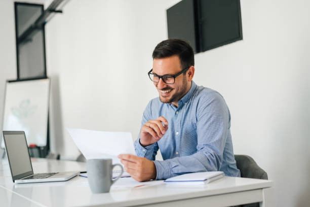 istock Young smiling cheerful confident businessman checking working plan and schedule or timetable in office copy space screen empty modern bright 1264621768