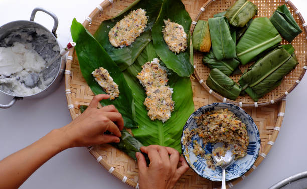 Woman hand making flat rice dumpling, stuffing from vegetable onto rice flour, vegan rice cake leaf from Hue
