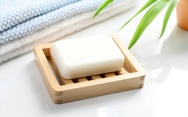 barra de jabón blanco sobre jabón de madera y toallas de algodón sobre una mesa blanca - jabonera fotografías e imágenes de stock