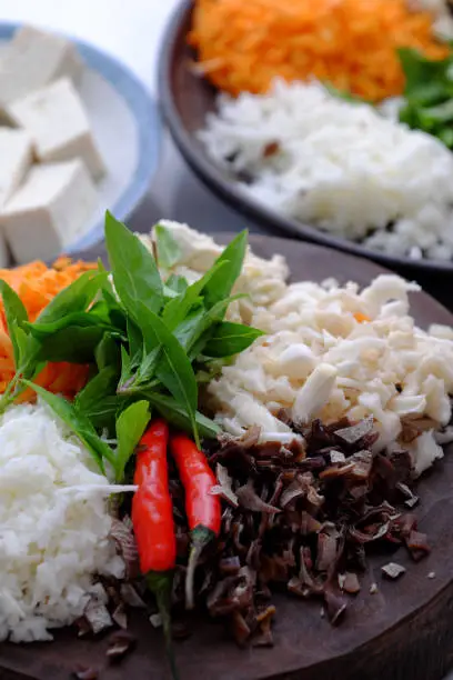 Top view raw material ready to cook homemade rice noodles roll, vegan ingredient as wood ear mushroom, carrot, rice batter, tofu that chopped on white background, Vietnamese popular dish