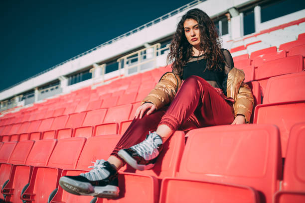młoda kobieta siedząca na pustym stadionie sportowym na świeżym powietrzu - stadium empty seat women zdjęcia i obrazy z banku zdjęć