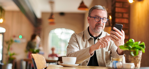 mature man in coffee shop with smartphone