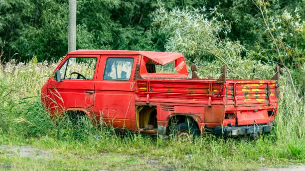 Photo of an old red car overgrown with grass