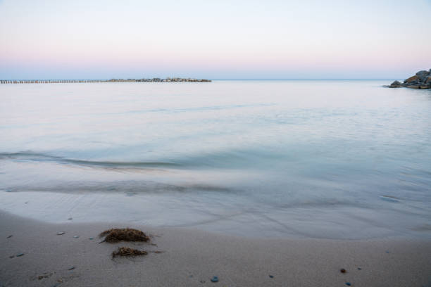 istock Calm evening sea surface with old stone pier and rocks. Evening seascape. 1264633269