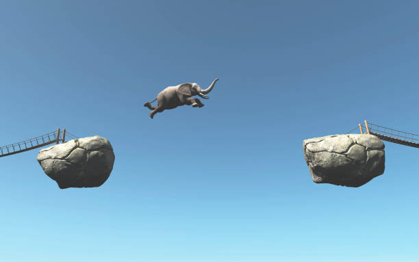 istock Elephant jumps over a gap between two rocks . Take the risk concept . This is a 3d render illustration . 1264634325