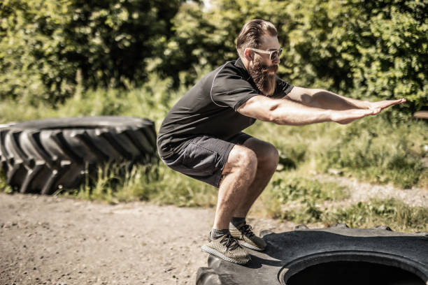 istock Young man doing balance exercise on tire on street background 1264634970