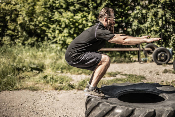 istock Young man doing balance exercise on tire on street background 1264637027
