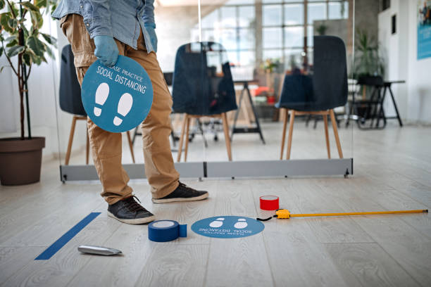 istock Man applying social distancing sign at office 1264640735