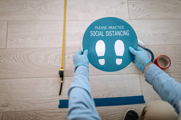istock Man applying social distancing sign at office 1264640762