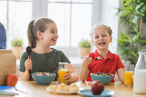 Happy children having breakfast. Kids eating cereal in kitchen.
