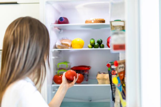 istock Young woman taking fresh healthy tomato vegetables from refrigerator, view from fridge 1264643158