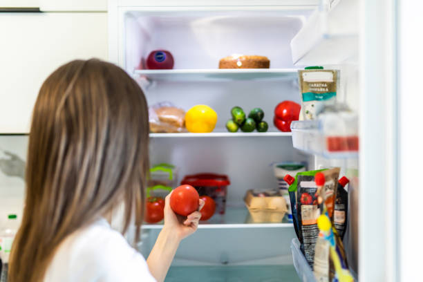 istock Young woman taking fresh healthy tomato vegetables from refrigerator, view from fridge 1264644604
