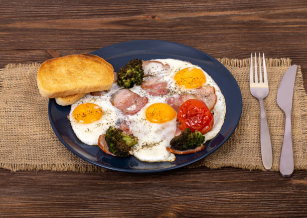 istock English breakfast with fried eggs, bacon, tomato, toasts and broccoli in the plate that is on burlap, on wooden background, angle view 1264648944