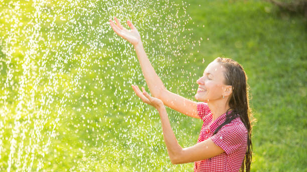 istock Happy young woman having fun under summer rain 1264650684