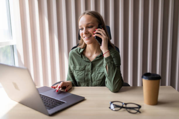 istock Beautiful young woman working on computer and talking on phone 1264651582